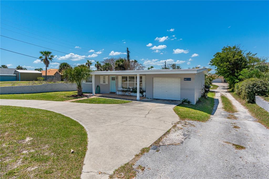 A single-story house with a light gray exterior, a white garage door, and a concrete driveway — 2908 S PENINSULA DRIVE, DAYTONA BEACH, FL
