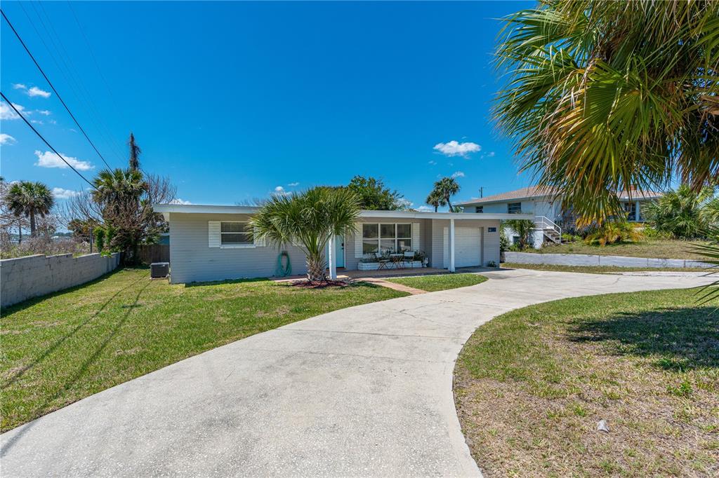 A single-story house with light gray siding, a concrete driveway, and a palm tree — 2908 S PENINSULA DRIVE, DAYTONA BEACH, FL