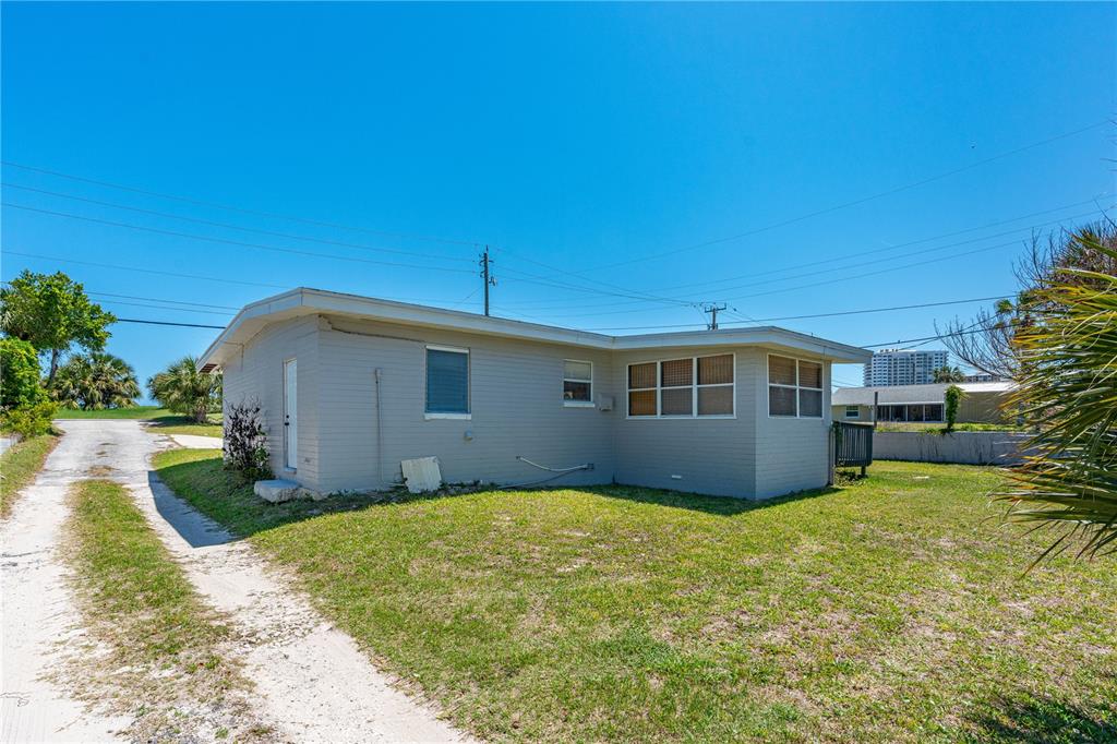 A light-colored, single-story house with a flat roof and a dirt driveway — 2908 S PENINSULA DRIVE, DAYTONA BEACH, FL