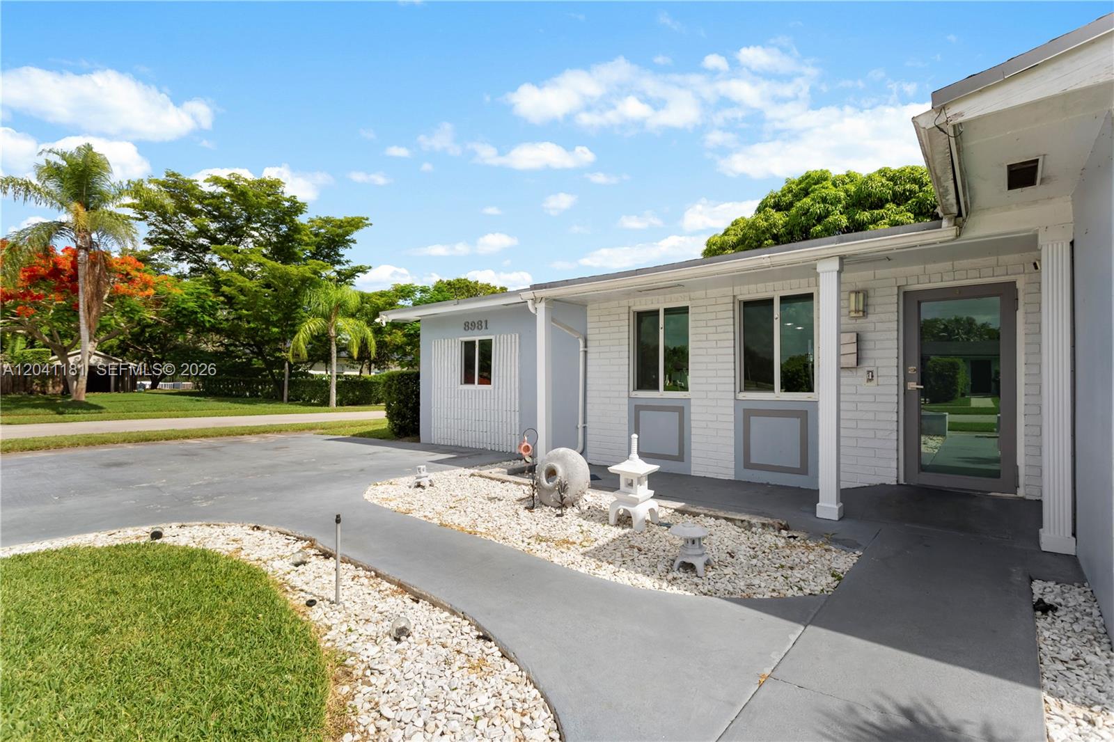 The exterior of a single-story building features white brick walls, a gray walkway, and decorative stone accents — 8981 SW 127th Ter, Miami FL 33176, MIAMI, FL