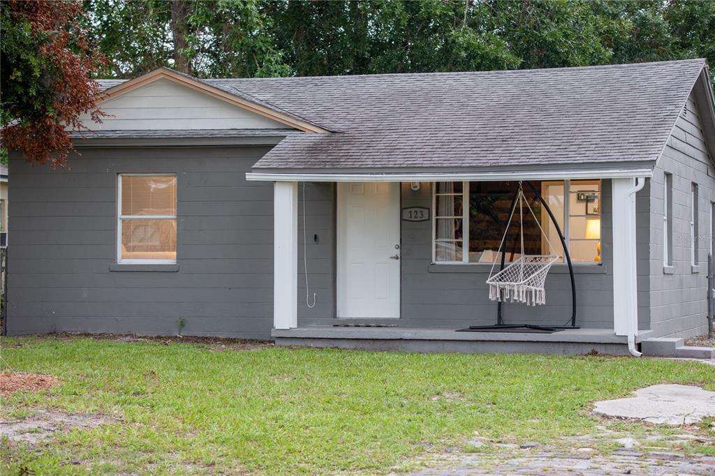 A gray, single-story house with a front porch, a white door, and a hanging chair — 123 OCONEE STREET, LAKELAND, FL