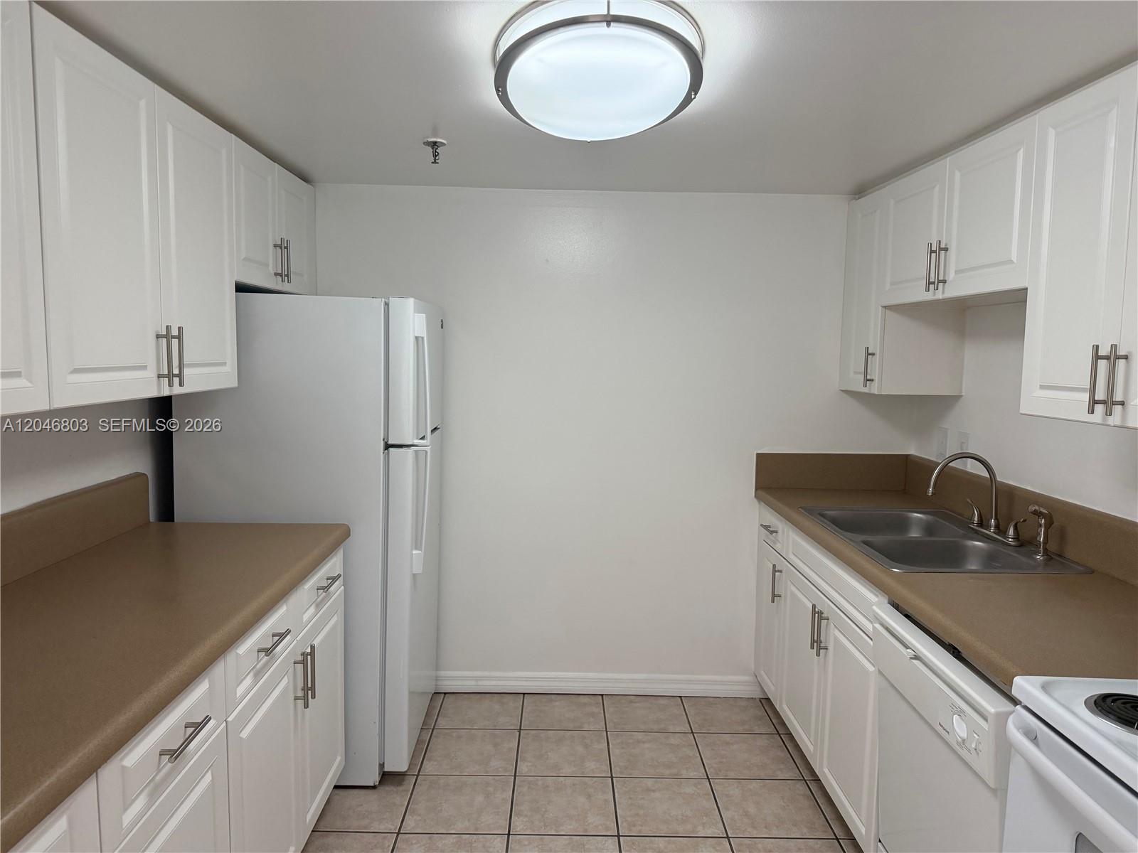 A kitchen features white cabinets, a white refrigerator, tan countertops, and a tile floor — 915 NW 1st Ave # H2208, Miami FL 33136, MIAMI, FL