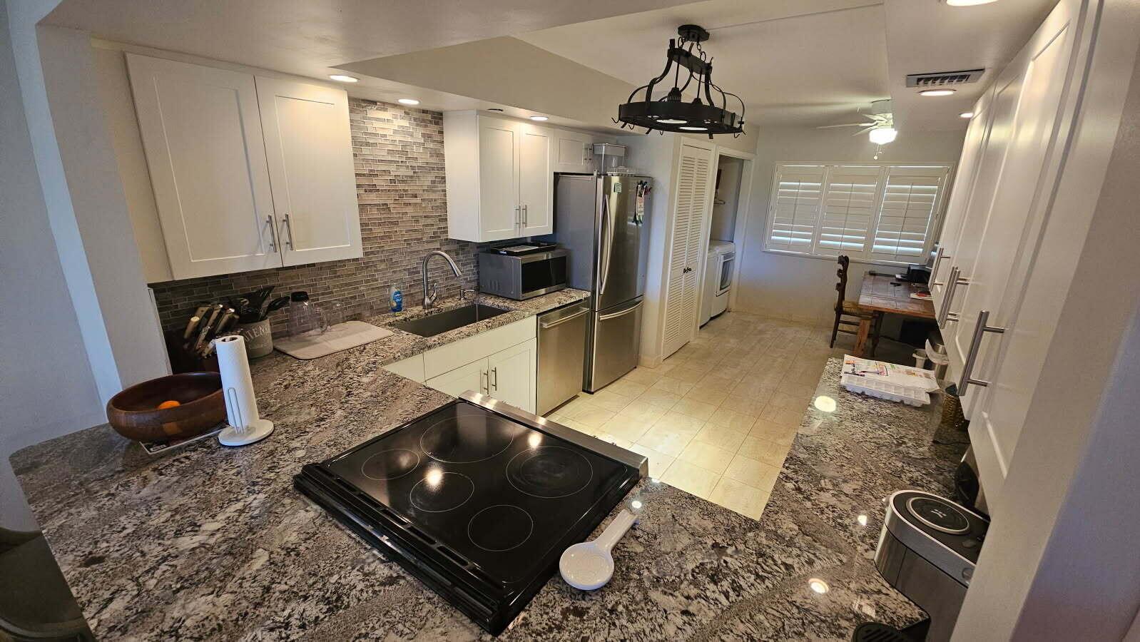 A kitchen features granite countertops, white cabinets, stainless steel appliances, and a tile backsplash — 500 Ocean Trail Way # 307, Jupiter FL 33477, JUPITER, FL