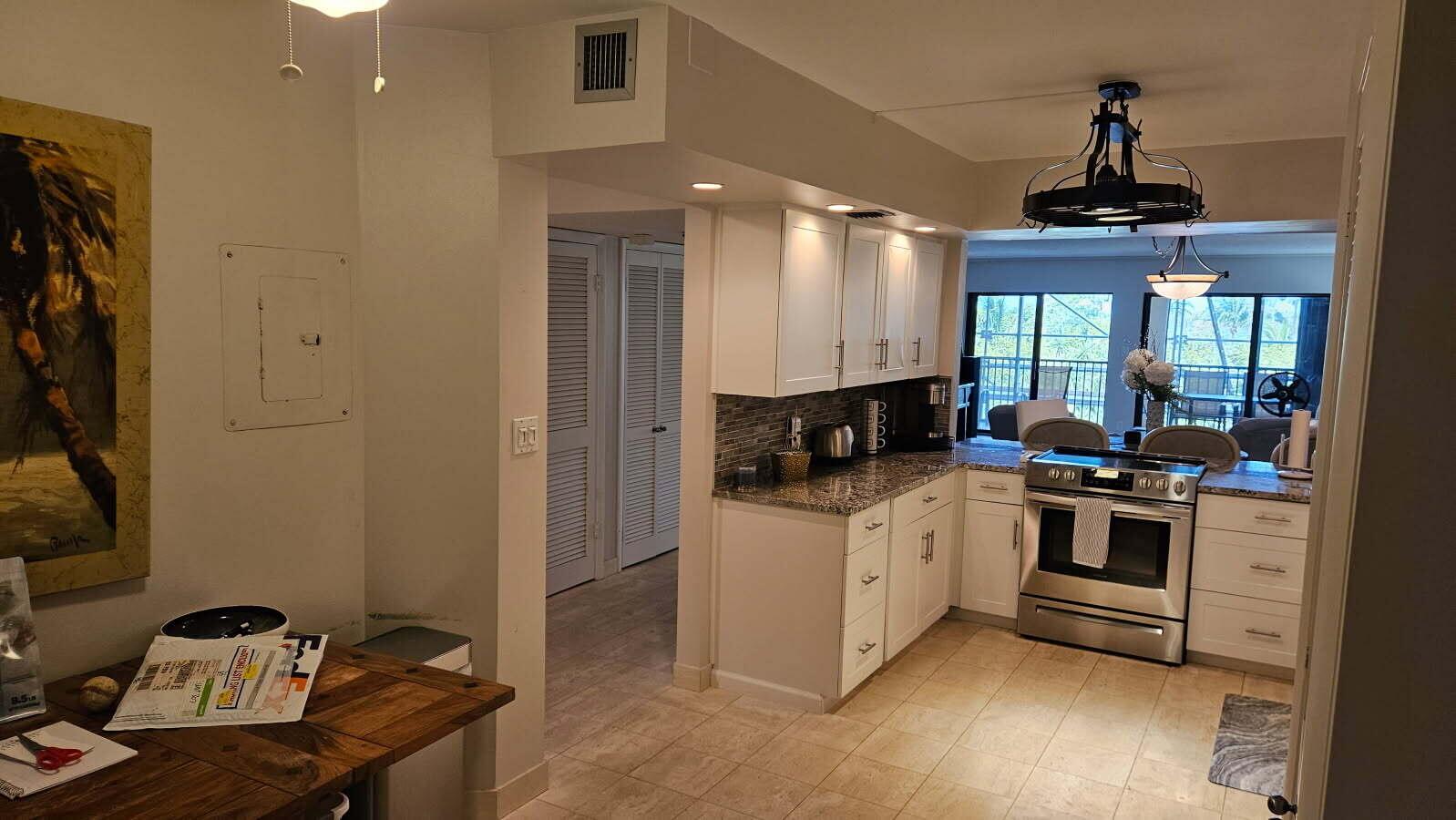 A kitchen with white cabinets, granite countertops, and stainless steel appliances opens to a living area — 500 Ocean Trail Way # 307, Jupiter FL 33477, JUPITER, FL