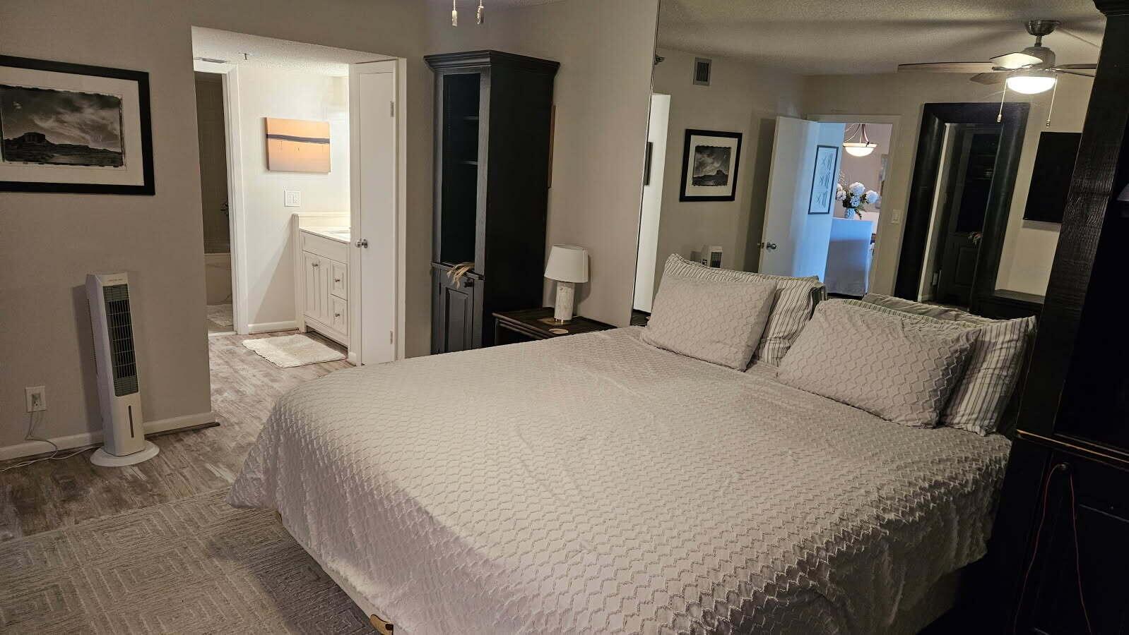 A bedroom features a large bed, a mirrored wall, and an open doorway to a bathroom — 500 Ocean Trail Way # 307, Jupiter FL 33477, JUPITER, FL
