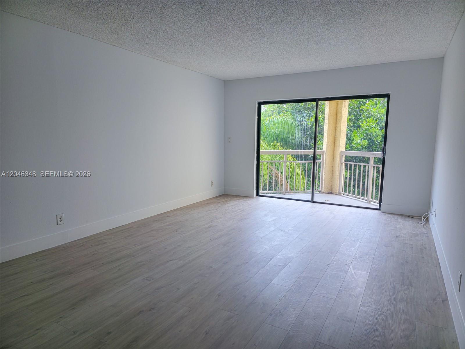An empty room with light wood-look flooring, white walls, and a sliding glass balcony door — 8290 Lake Dr # 422, Doral FL 33166, DORAL, FL