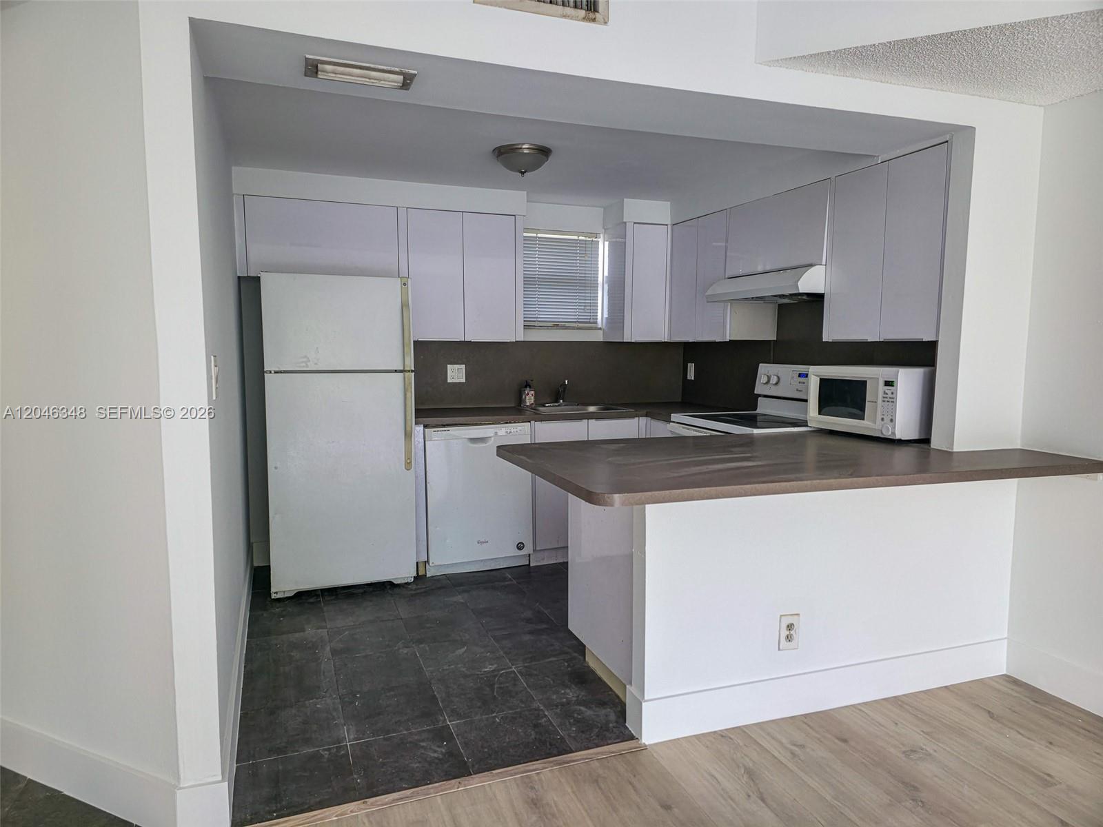 A kitchen features white cabinets, a white refrigerator, a dishwasher, and a brown countertop — 8290 Lake Dr # 422, Doral FL 33166, DORAL, FL