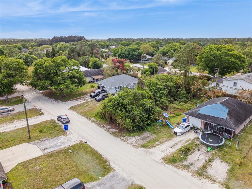 An aerial view shows residential houses, dirt roads, trees, and parked vehicles in a neighborhood — 1335 25TH AVENUE SW, VERO BEACH, FL