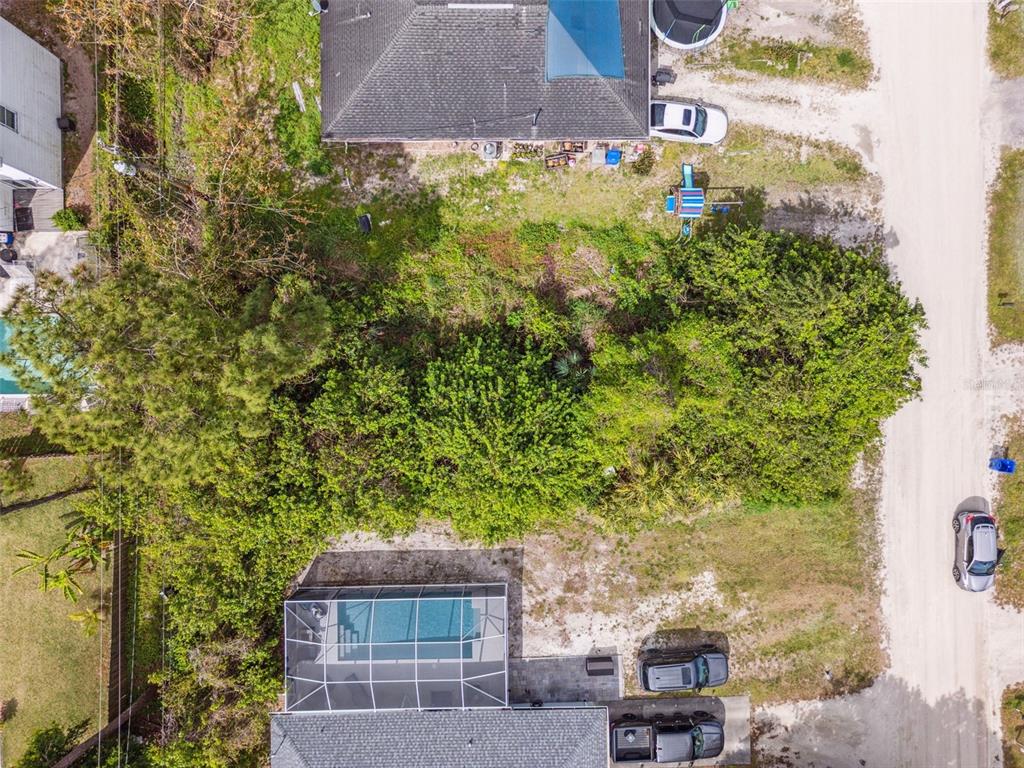 An aerial view shows a house with a pool cage and a large wooded lot — 1335 25TH AVENUE SW, VERO BEACH, FL