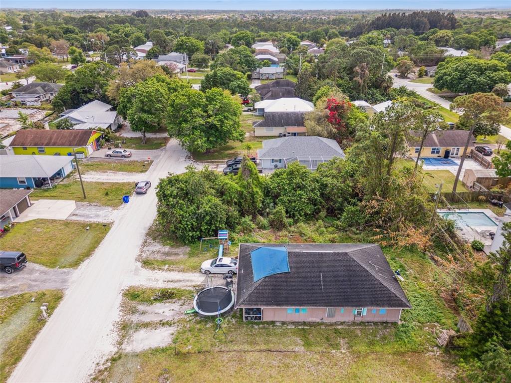 An aerial view shows a residential neighborhood with houses, trees, and a dirt road — 1335 25TH AVENUE SW, VERO BEACH, FL