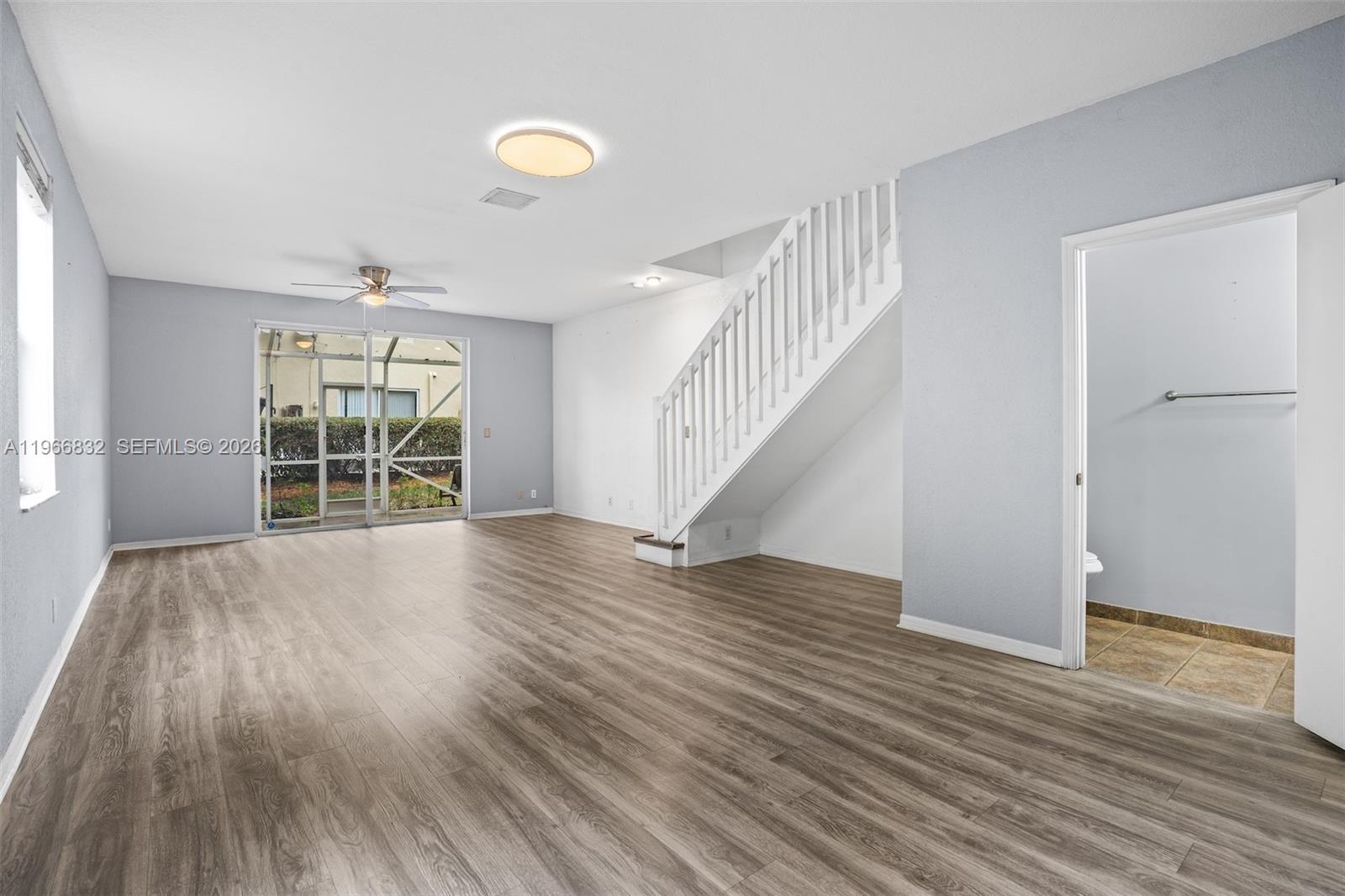 An open living area features wood-look flooring, a staircase, and a sliding glass door — 2167 Hacienda Ter, Weston FL 33327, WESTON, FL
