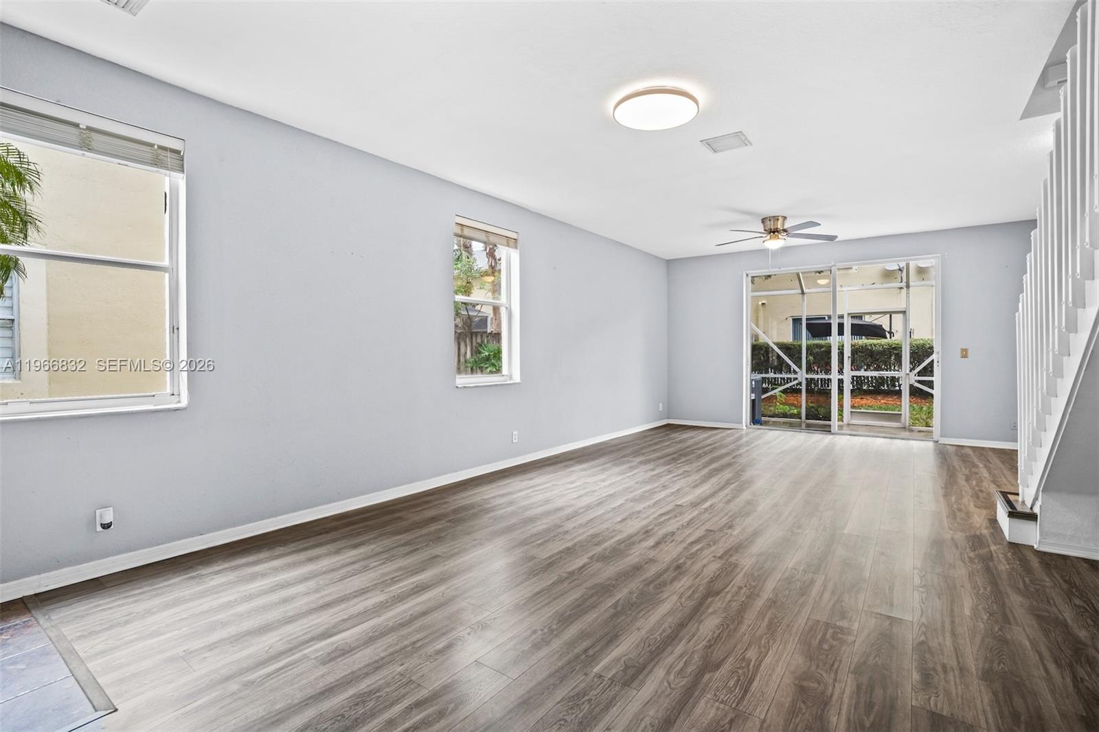 An empty living room features light gray walls, wood-look flooring, a ceiling fan, and stairs — 2167 Hacienda Ter, Weston FL 33327, WESTON, FL