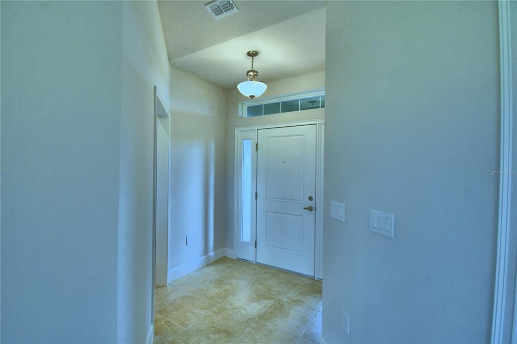 An entryway features a white front door, tile flooring, and a hanging light fixture — 4607 CALAMINT LANE, AUBURNDALE, FL