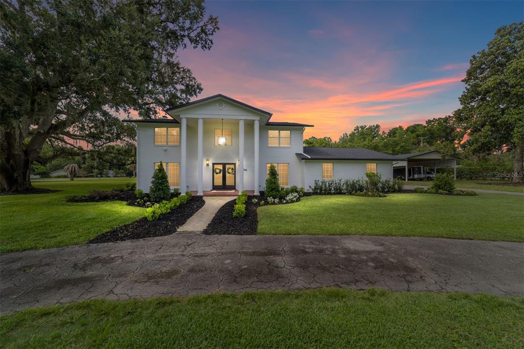 A two-story white house with columns stands on a grassy lawn at sunset — 4824 SE 3RD STREET, OCALA, FL