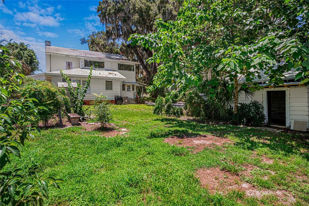 A two-story white house and a small detached shed sit in a grassy backyard — 102 PALMORA BOULEVARD, LEESBURG, FL