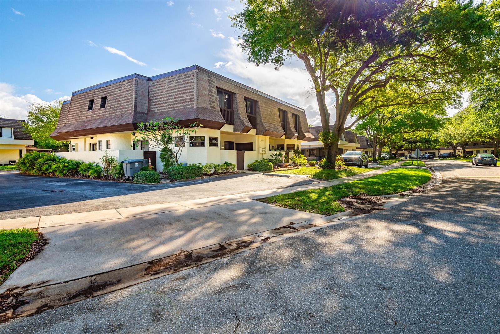 A two-story residential building with a mansard roof sits beside a paved street and trees — 9375 SW 61st Way SW # D, Boca Raton FL 33428, BOCA RATON, FL