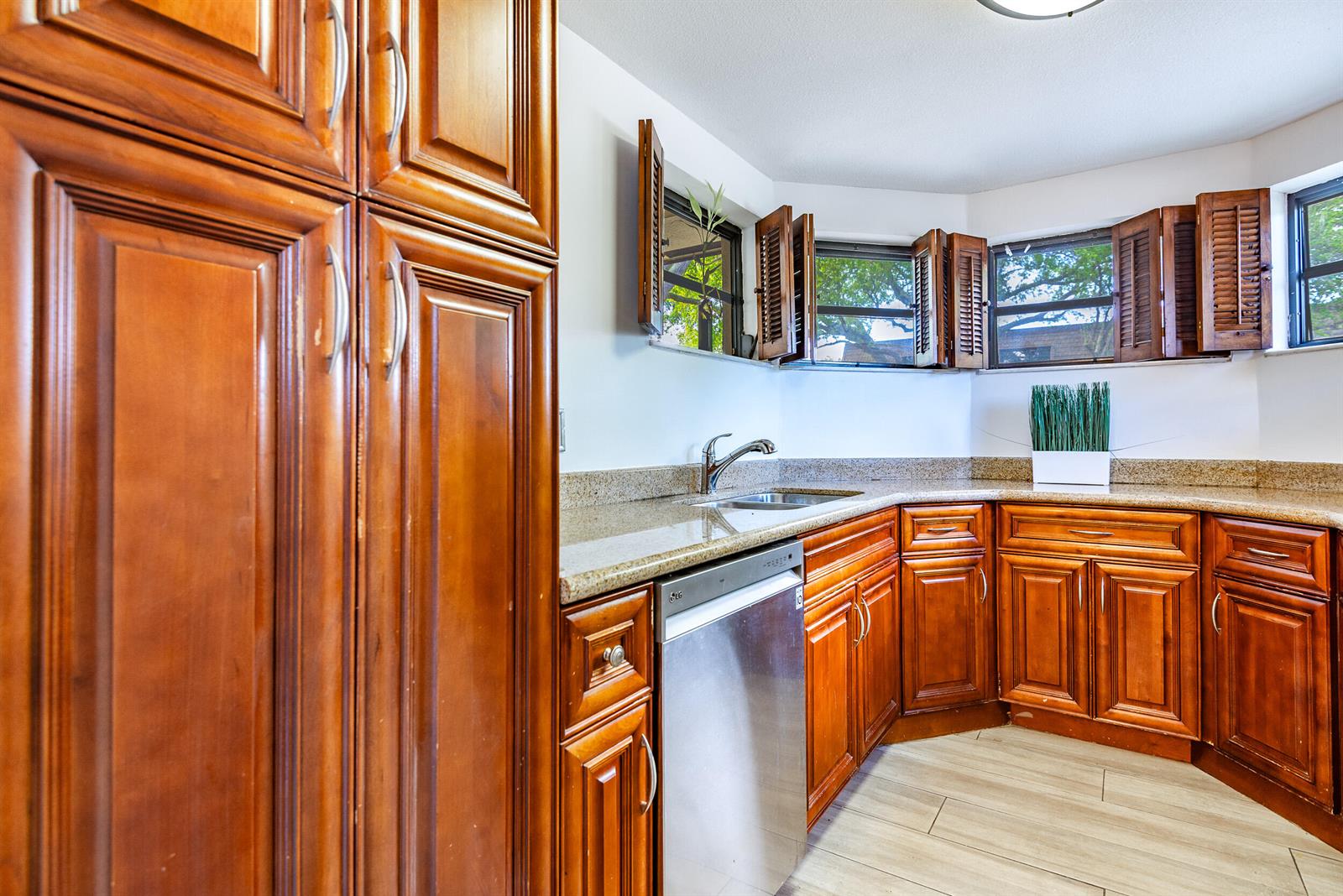 A kitchen features wood cabinets, granite countertops, a stainless steel dishwasher, and windows with shutters — 9375 SW 61st Way SW # D, Boca Raton FL 33428, BOCA RATON, FL