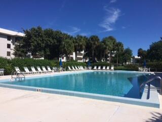 A large rectangular swimming pool sits in front of a multi-story building and palm trees — 3636 Whitehall Drive # 204, West Palm Beach FL 33401, WEST PALM BEACH, FL