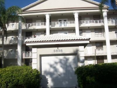 A multi-story apartment building features white columns, balconies, and a ground-level garage entrance — 3636 Whitehall Drive # 204, West Palm Beach FL 33401, WEST PALM BEACH, FL