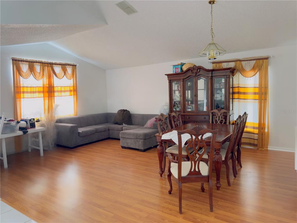 A living and dining area with wood-look flooring, a grey sectional, and a wooden hutch — 4450 MALVERN HILL DRIVE, ORLANDO, FL
