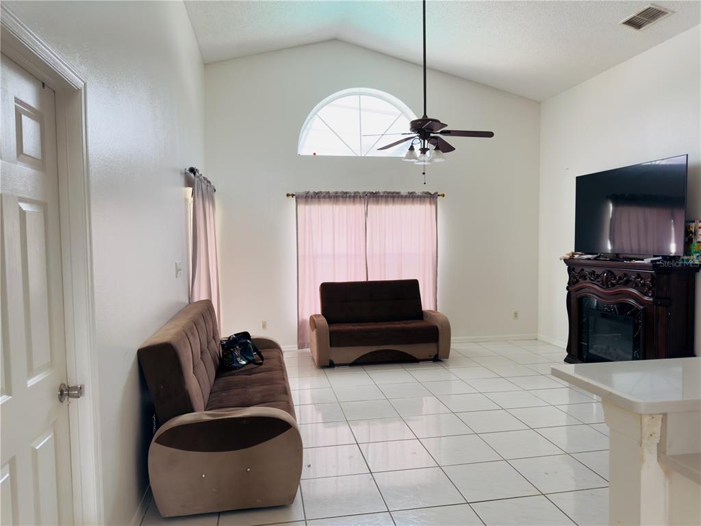 A living room features white tile floors, vaulted ceilings, a fireplace, and two brown sofas — 4450 MALVERN HILL DRIVE, ORLANDO, FL