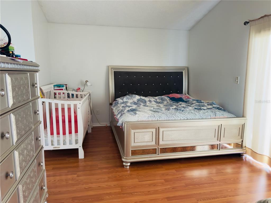A bedroom features a metallic bed frame, a white crib, and a matching dresser on wood flooring — 4450 MALVERN HILL DRIVE, ORLANDO, FL
