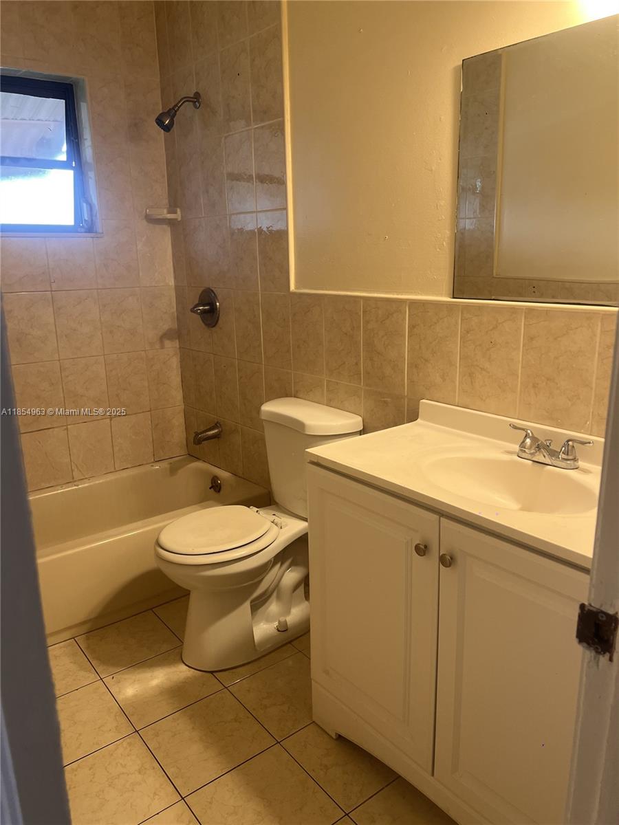 A bathroom features a tiled shower-tub combination, a white vanity, and a toilet — 6150 Dawson St # 0, Hollywood FL 33023, HOLLYWOOD, FL