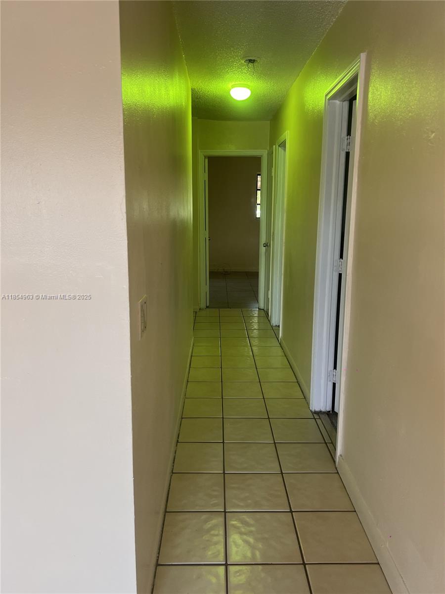 A narrow hallway features light-colored walls, a tiled floor, and a single ceiling light fixture — 6150 Dawson St # 0, Hollywood FL 33023, HOLLYWOOD, FL