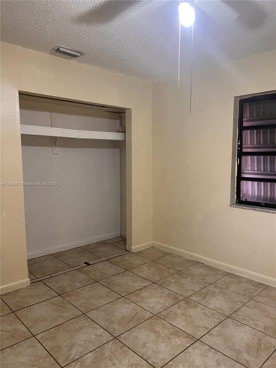 A room with beige walls, tiled flooring, a ceiling fan, and an open closet — 6150 Dawson St # 0, Hollywood FL 33023, HOLLYWOOD, FL