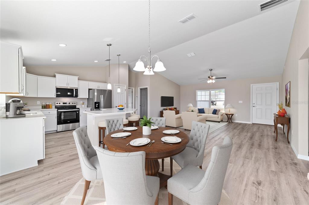 An open-concept kitchen, dining area, and living room featuring light wood floors and white cabinetry — 15159 SW 29TH STREET, OCALA, FL