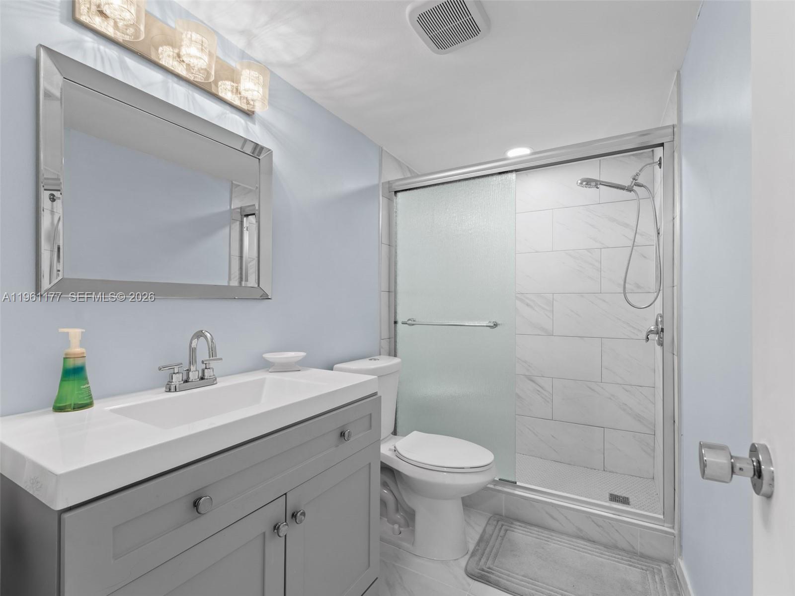 A bathroom features a gray vanity, a white toilet, and a glass-enclosed tiled shower — 2601 NE 3rd Ct # 4030, Boynton Beach FL 33435, BOYNTON BEACH, FL