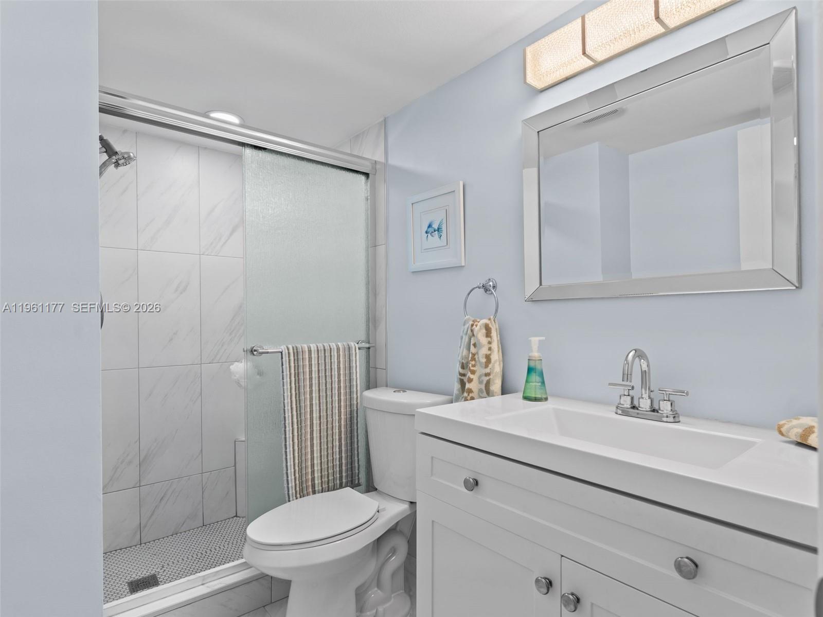 A bathroom features a white vanity, a toilet, and a glass-enclosed shower with tiled walls — 2601 NE 3rd Ct # 4030, Boynton Beach FL 33435, BOYNTON BEACH, FL