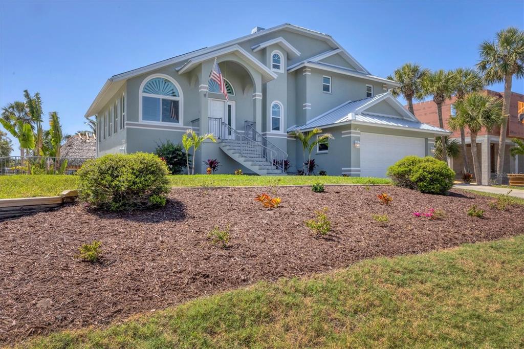 A two-story house with a light green exterior, a white garage, and a landscaped yard — 10500 SHERMAN STREET, ENGLEWOOD, FL