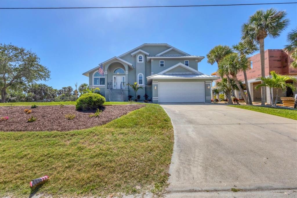 A two-story light green house with a white garage and palm trees in the yard — 10500 SHERMAN STREET, ENGLEWOOD, FL