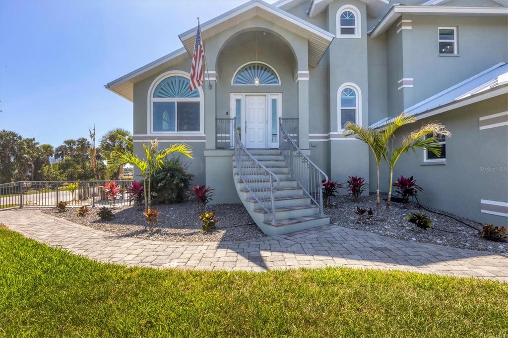 A two-story house with a raised entryway, arched windows, and a paved walkway — 10500 SHERMAN STREET, ENGLEWOOD, FL