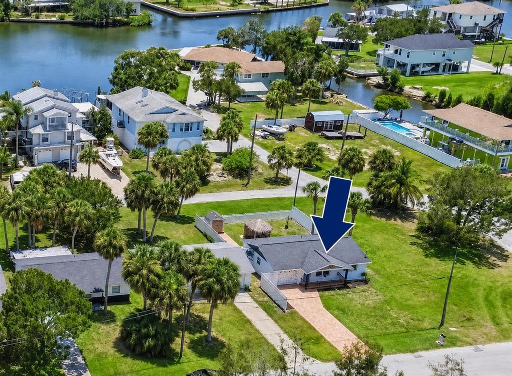 An aerial view shows a single-story house with a dark roof and a paved driveway — 6814 DRIFTWOOD DRIVE, HUDSON, FL