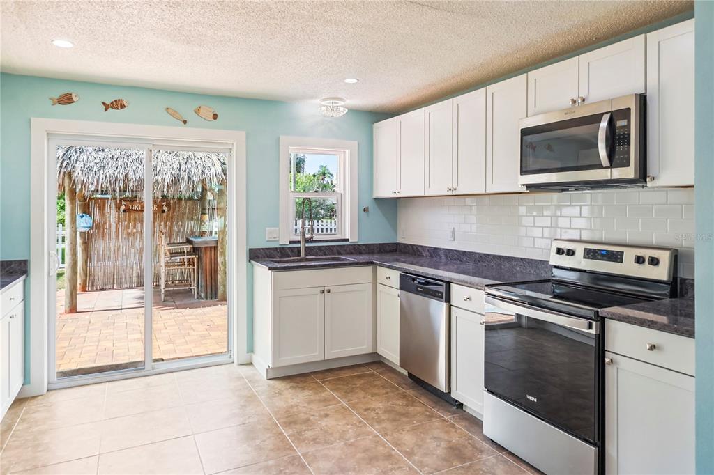 A kitchen with white cabinets, stainless steel appliances, and a sliding door to a patio — 6814 DRIFTWOOD DRIVE, HUDSON, FL