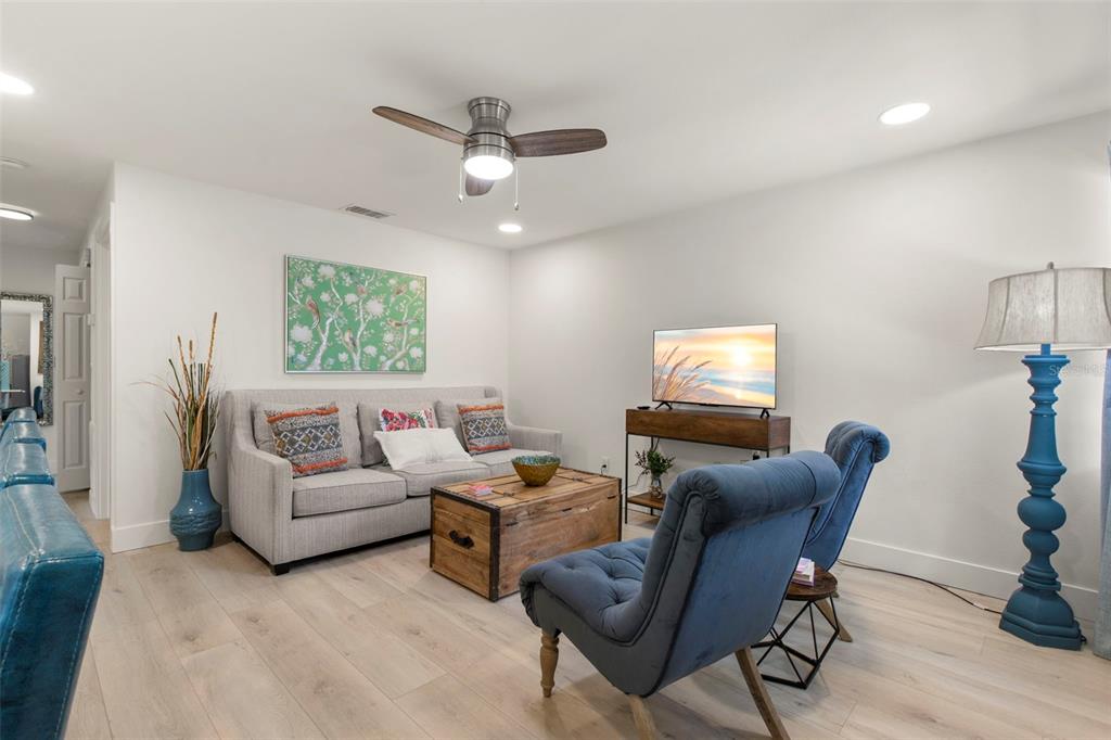 A living room features a gray sofa, blue armchairs, a wooden coffee table, and flooring — 415 MAPLE WAY UNIT A & B, SAFETY HARBOR, FL