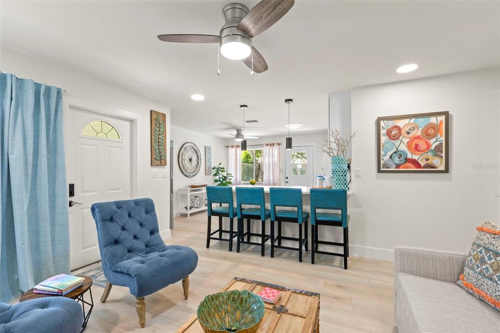 A living room with a blue armchair, bar seating, and light wood flooring — 415 MAPLE WAY UNIT A & B, SAFETY HARBOR, FL