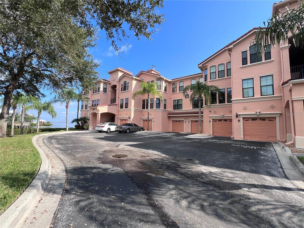 A multi-story pink apartment building with attached garages and a parking lot — 2755 VIA CAPRI DRIVE UNIT 1226, CLEARWATER, FL