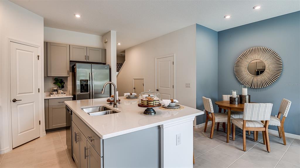 A kitchen with a central island, stainless steel appliances, and an adjacent dining area — 8433 LUNAR SKYE STREET, SARASOTA, FL