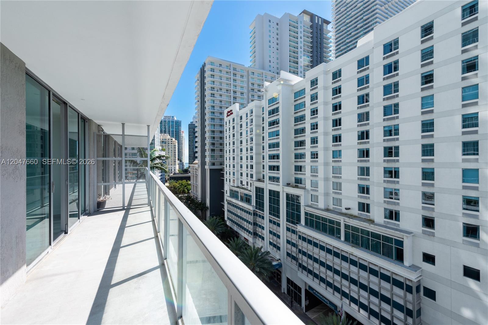 A balcony with a glass railing overlooks a dense urban area with several high-rise buildings — 79 SW 12th St, Miami FL 33130, MIAMI, FL