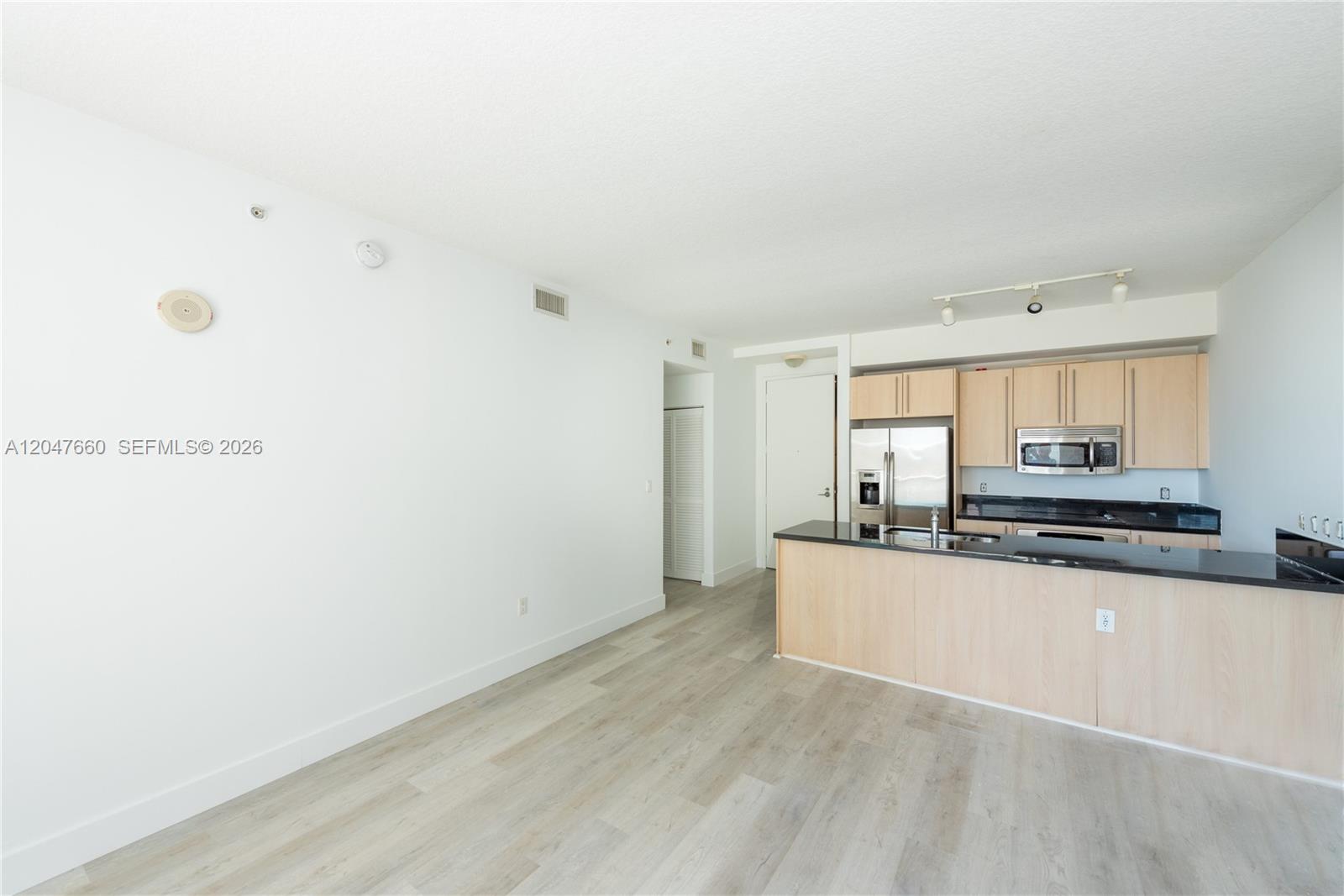 This room features light wood-look flooring, white walls, and an open kitchen with light wood cabinets — 79 SW 12th St, Miami FL 33130, MIAMI, FL