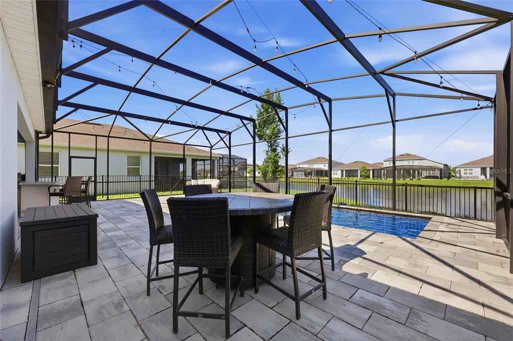 A screened-in patio features a dining set, a small pool, and a view of a pond — 13932 DESTIN BEACH LANE, ORLANDO, FL
