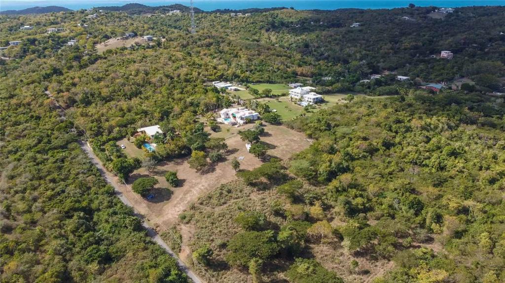 An aerial view shows several houses with swimming pools nestled within a lush, hilly landscape — 55 CALLE LA LLAVE, VIEQUES, PR