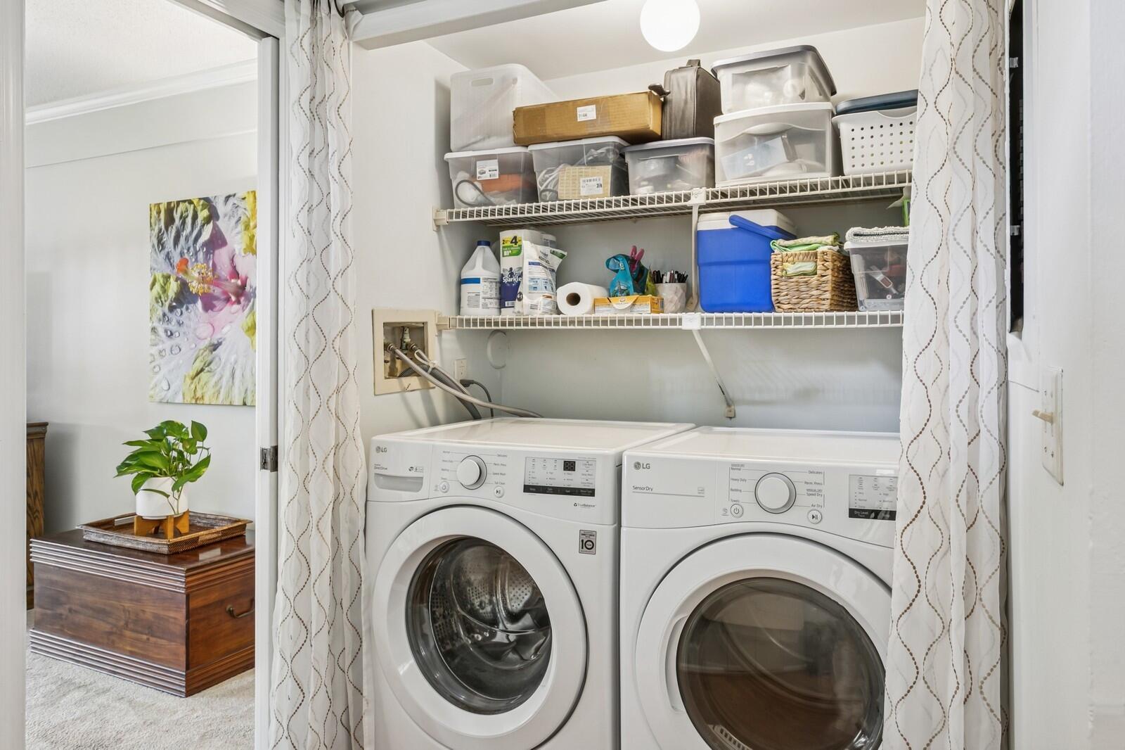 A laundry closet with white appliances, wire shelving, and patterned curtains in a residential interior — 24 Uno Lago Drive, Juno Beach FL 33408, JUNO BEACH, FL