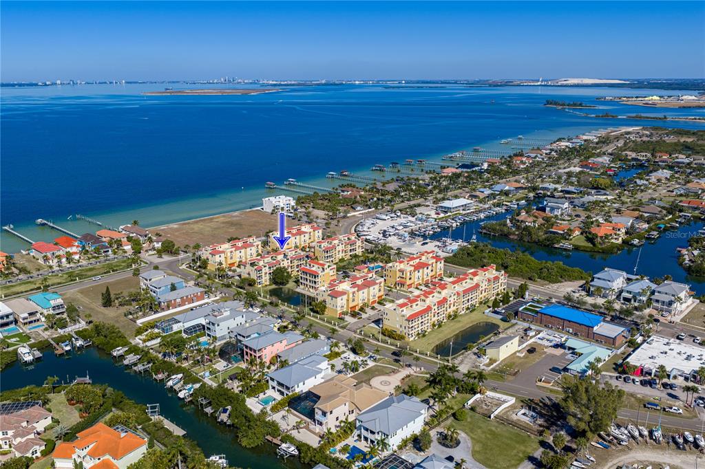 An aerial view shows a multi-story residential complex near a bay with docks — 6411 MAYRA SHORES LANE, APOLLO BEACH, FL