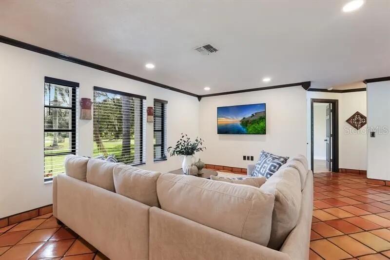 A living room features a beige sectional sofa, tile flooring, and windows overlooking a yard — 2077 RACIMO DRIVE, SARASOTA, FL