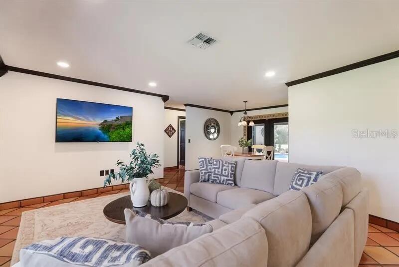 A living room with a large sectional sofa, a wall-mounted television, and terracotta tile flooring — 2077 RACIMO DRIVE, SARASOTA, FL