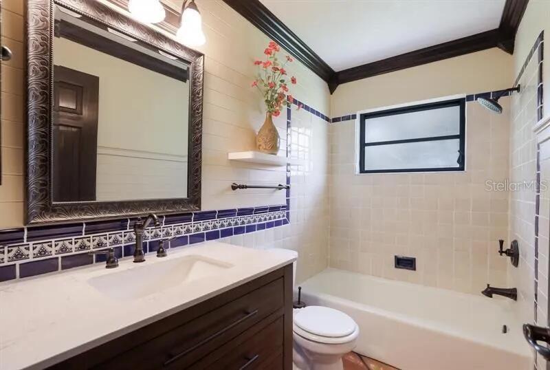 A bathroom features a vanity with a white countertop, a mirror, and a tiled tub — 2077 RACIMO DRIVE, SARASOTA, FL